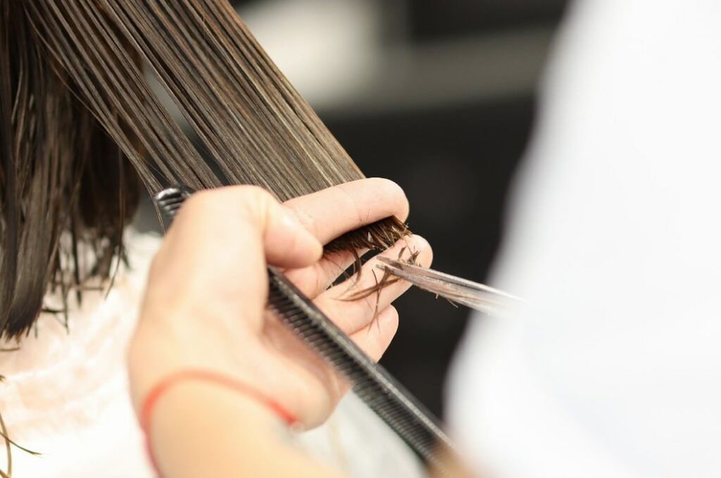 Der Friseur hält das nasse Haar der Kundin und schneidet es in Bielefeld